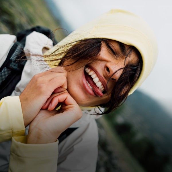Una donna in abbigliamento outdoor estivo sta in equilibrio su una roccia in riva a un lago