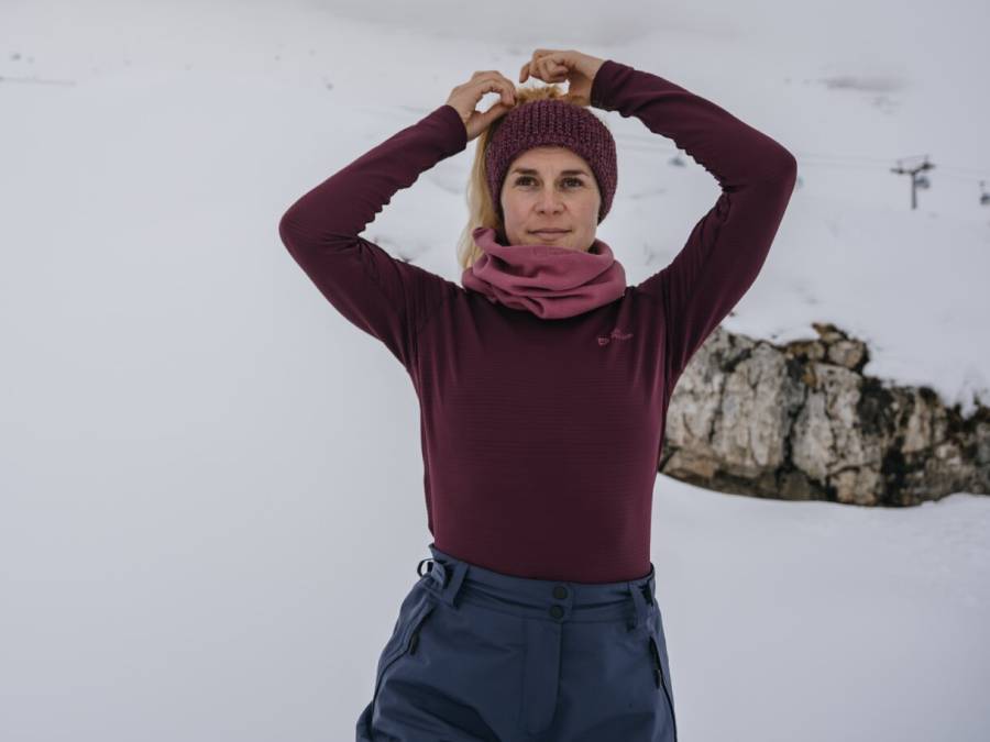 Frau in warmem Baselayer in verschneiter Berglandschaft