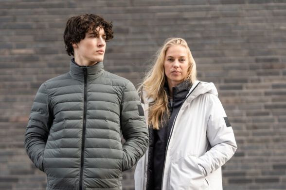 Una donna e un uomo in giacche invernali casual davanti a un muro