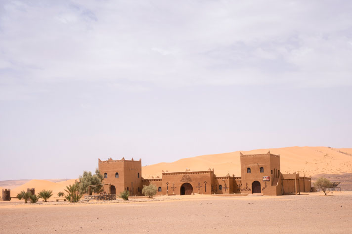 Braunes Gebäude mit Palmen in einer Wüste