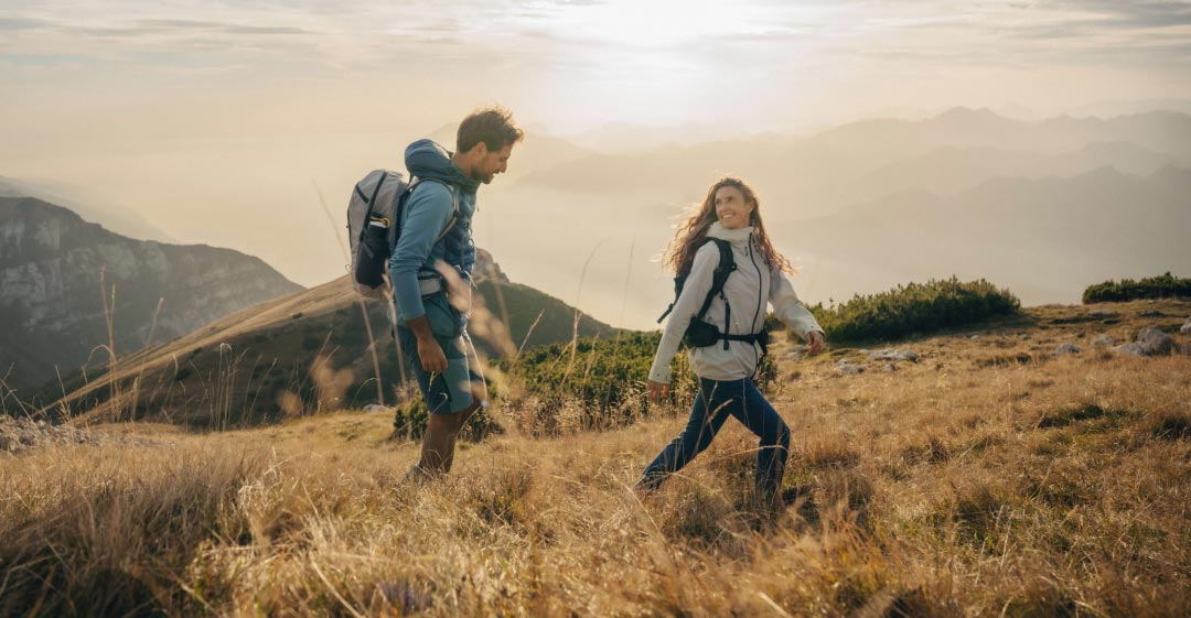 Frau und Mann in herbstlicher Outdoor-Kleidung in bergiger Landschaft