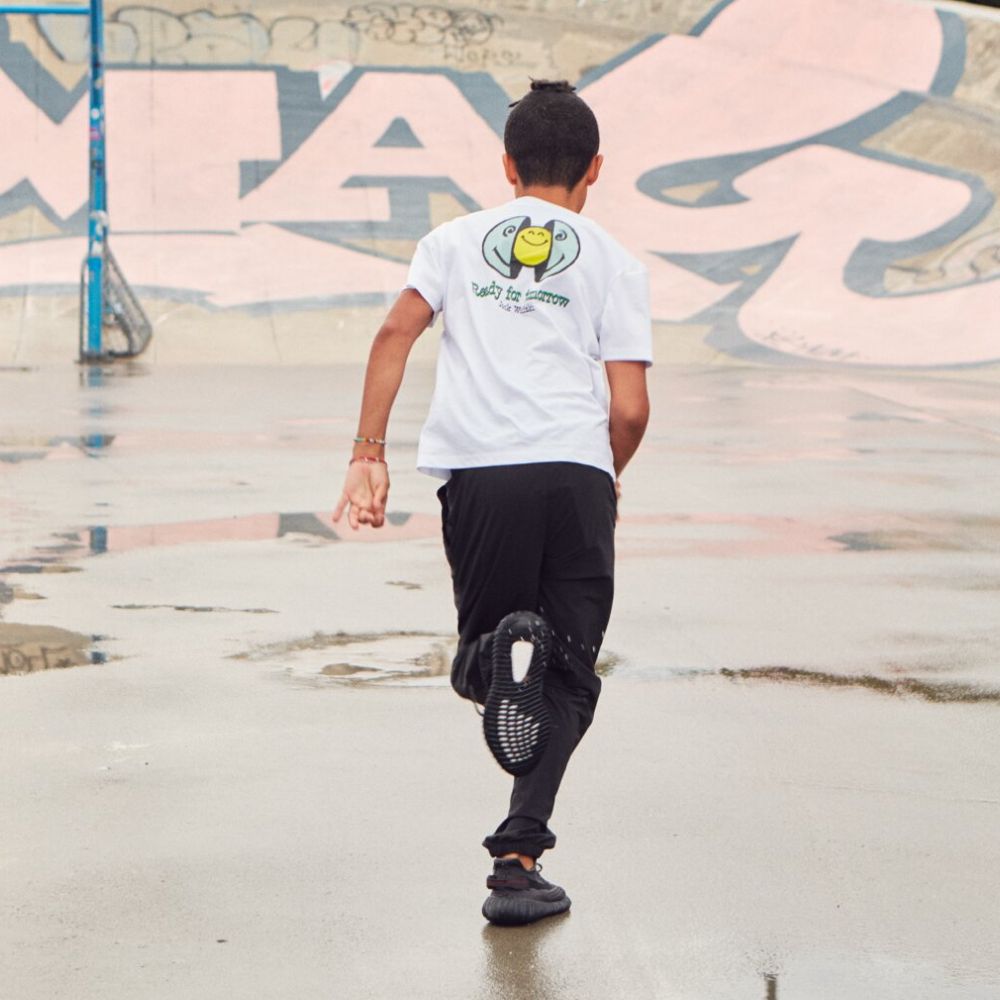 Junge läuft auf Asphalt mit Graffiti im Hintergrund