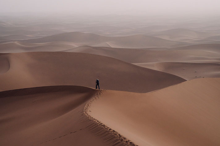 Ein Mann steht auf einer Düne in der Sandwüste