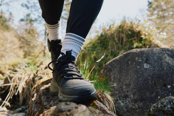 Primo piano di una persona con scarpe da escursionismo mentre cammina su una roccia